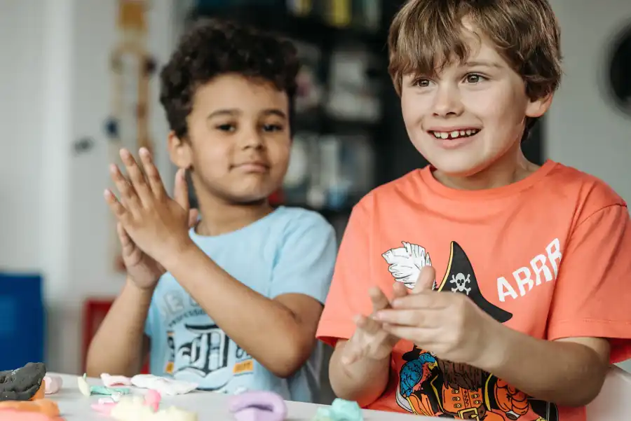Dois meninos batendo palmas e sorrindo durante uma atividade