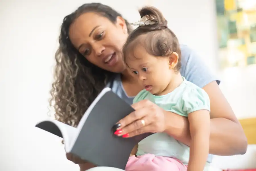 Educadora lendo um livro com uma criança no colo